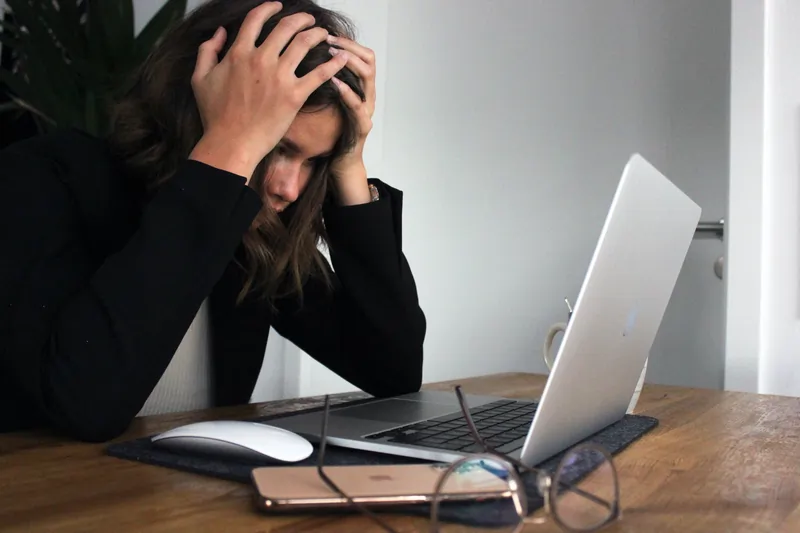 Lady in front of a computer holding her head