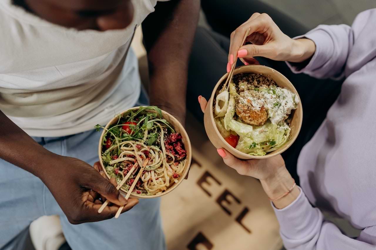 A couple holding two bowls of healthy meals